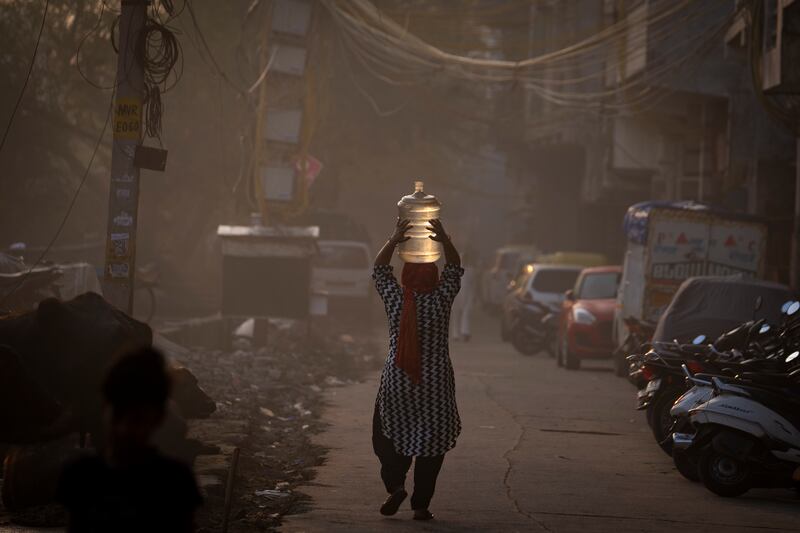 A woman returns home after collecting drinking water from a tanker on World Water Day in New Delhi, India. Wednesday is the 30th anniversary of World Water Day. AP Photo