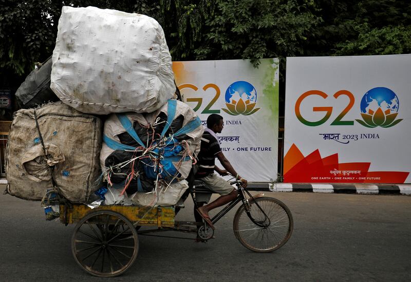 A man rides his trishaw past hoardings installed alongside a pavement ahead of the G20 summit in New Delhi, India. Reuters