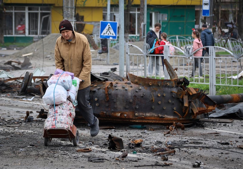 Residents walk near a damaged military vehicle in an area controlled by Russian-backed separatist forces in Mariupol. AP