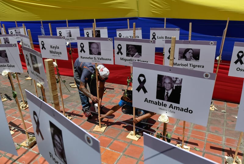 Workers place signs with portraits of health workers who died from Covid-19 at the Venezuelan Medical Federation in Caracas, Venezuela. AFP
