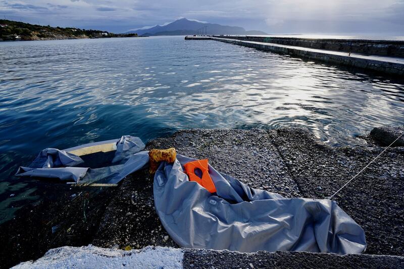 SAMOS, Greece.  November 28 2019.

A half-sunken inflatable boat lies abandoned in the port of Pythagorio in Samos, Greece.  In the distance, the outline of Turkey just a few miles away. Boats such as these are used by smugglers to transport refugees from Turkey to Greece.  (Photo by Giles Clarke/Getty Images)