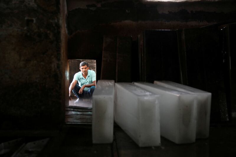 At a factory in New Delhi, a worker waits to load ice blocks on to a vehicle. Reuters