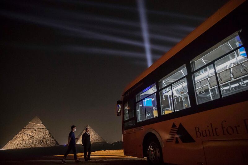 A general view of (background R to L) the Great Pyramid of Khufu (Cheops) and the Pyramid of Khafre (Chephren) at the Giza Pyramids necropolis on the southwestern outskirts of the Egyptian capital Cairo during an official ceremony launching the trial operations of the site's first environmentally-friendly electric bus (foreground) and restaurant as part of a wider development plan at the necropolis.   AFP