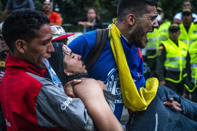 Demonstrators carry a wounded man during a clashes on the Simon Bolivar International Bridge. Bloomberg