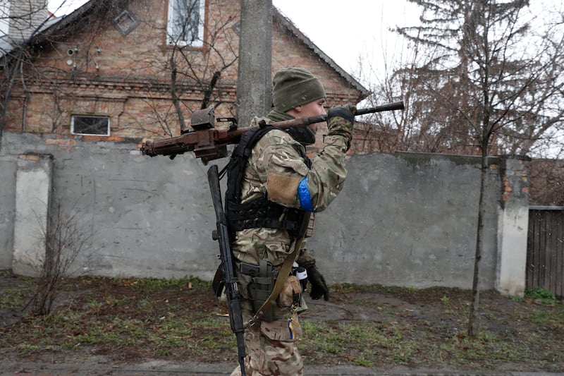 A Ukrainian soldier carries a machine gun salvaged from a destroyed Russian military machine in the areas recaptured by the Ukrainian army in Bucha. EPA