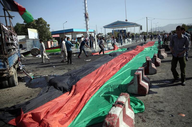 Afghans use a banner in the colours of the Afghan flag to cover victim's blood, after a deadly explosion struck a protest march by ethnic Hazaras, in Kabul, Afghanistan, Saturday, July 23, 2016. (AP Photos/Massoud Hossaini)