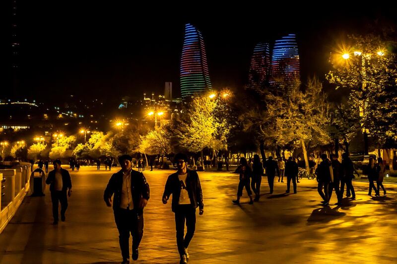 epa07538098 People walk along the Caspian seaside with the Flame Towers in background in Baku, Azerbaijan, late 29 April 2019. The Olympic Stadium in Baku has been selected to host the 2019 UEFA Europa League final on 29 May 2019, the first such fixture to be played in Azerbaijan  EPA/SRDJAN SUKI