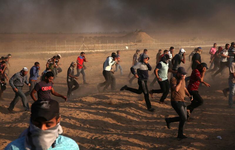 Protester run to take cover from teargas fired by Israeli troops while others burn tires near the fence of the Gaza Strip border with Israel during the protest. AP Photo
