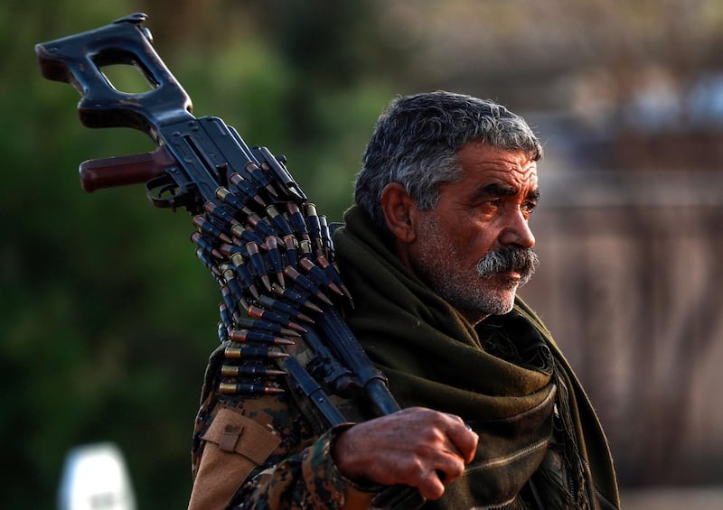 A Syrian Democratic Forces'(SDF) fighter holds a machine gun on his shoulder as he attends the funeral of a slain People's Protection Units (YPG) commander in the northeastern city of Qamishli on December 6, 2018.  / AFP / Delil SOULEIMAN
