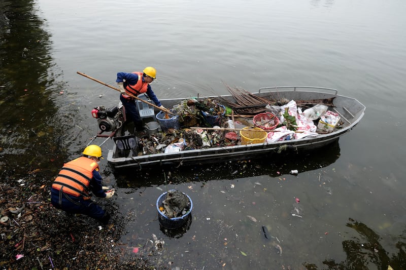 Workers remove waste from West Lake in Hanoi, Vietnam.  EPA 