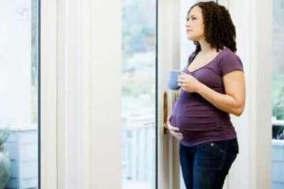 Pregnant African woman looking out window