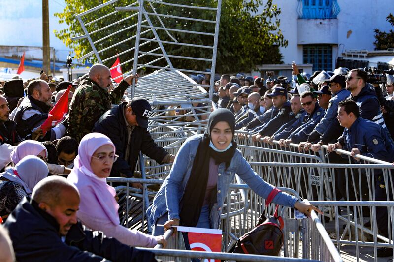 Tunisian demonstrators remove metal barriers during scuffles with security forces. AFP