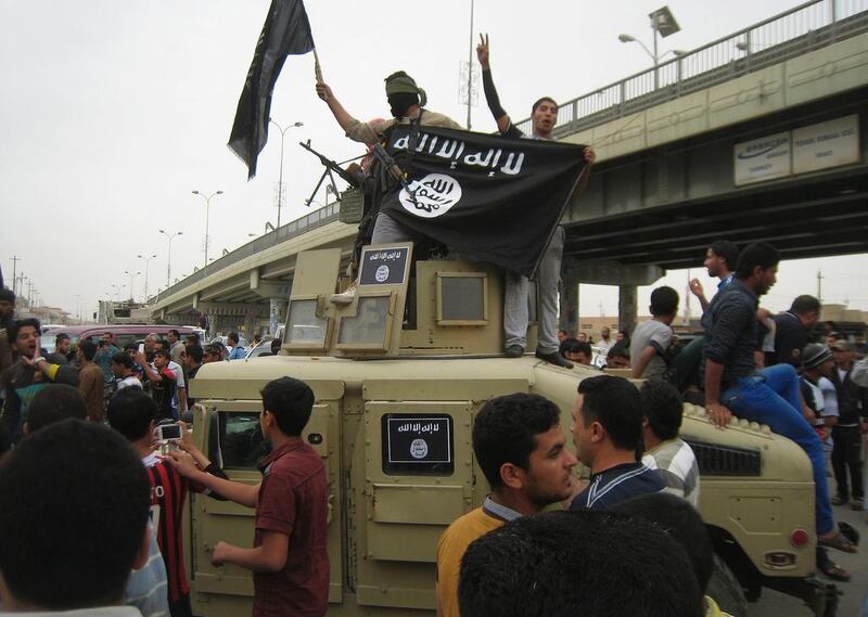 ISIL militants wave the group's flag from a commandeered Iraqi military vehicle in Fallujah. Photo: AP