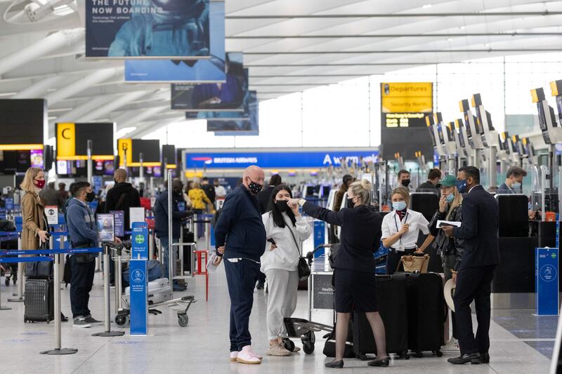 A member of staff directs passengers at check-in desks at London Heathrow. Bloomberg