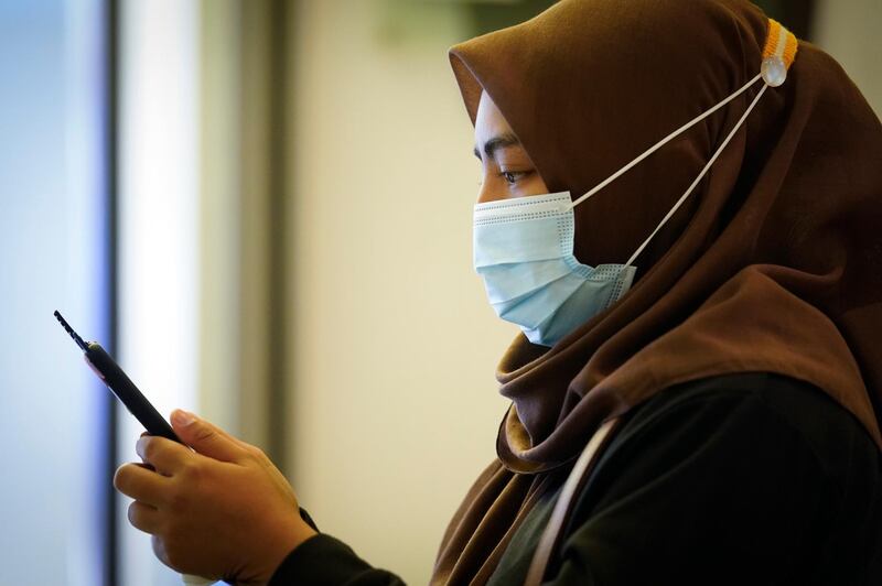 A woman wearing a face mask to help curb the spread of the coronavirus reads from her mobile phone at a shopping mall in Putrajaya, Malaysia, Thursday, Oct. 1, 2020. Thursday's new COVID-19 infections made it the second highest increase since the recovery movement control order (MCO) phase began on June 9. (AP Photo/Vincent Thian)