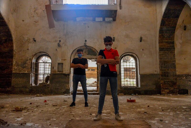 Iraqi men, wearing protective masks to combat the coronavirus, pray inside a destroyed mosque in the northern Iraqi city of Mosul.   AFP