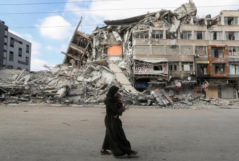 A Palestinian woman carries her son as she flees her home during Israeli strikes. Reuters