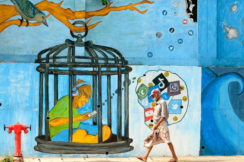 A man wearing a face mask as a preventive measure against the Covid-19 coronavirus walks past a mural in Colombo.  AFP