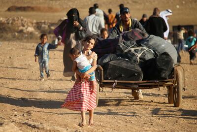 TOPSHOT - Syrian refugees carry belongings as they return to Syria after crossing the Jordanian border near the town of Nasib, in the southern province of Daraa, on August 29, 2017. / AFP PHOTO / Mohamad ABAZEED