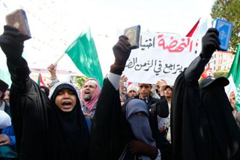 An Ennahda supporter ruling holds up a Quran as others shout slogans during a demonstration in Tunis on Saturday. Anis Mili / Reuters