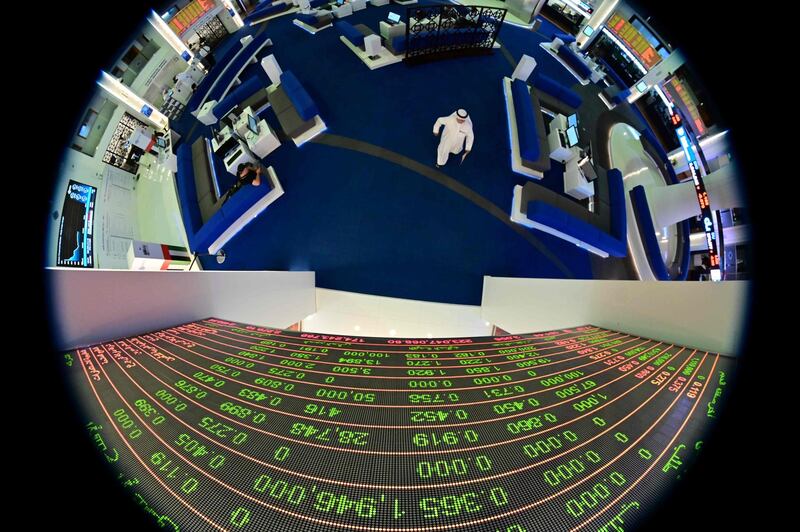 A picture taken with a fisheye lense shows traders walking by beneath a stock display board at the Dubai Stock Exchange in the the UAE.  AFP