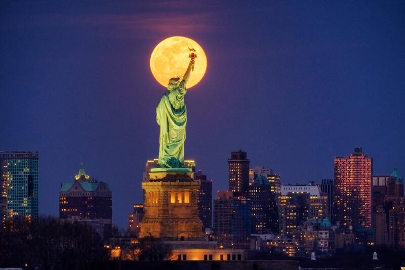 The rising full moon crosses behind the Statue of Liberty, Monday evening, March 9, 2020, in New York City. AP Photo