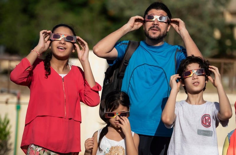 Members of a family use special protective glasses to observe an annular partial solar eclipse in Cairo, Egypt. EPA