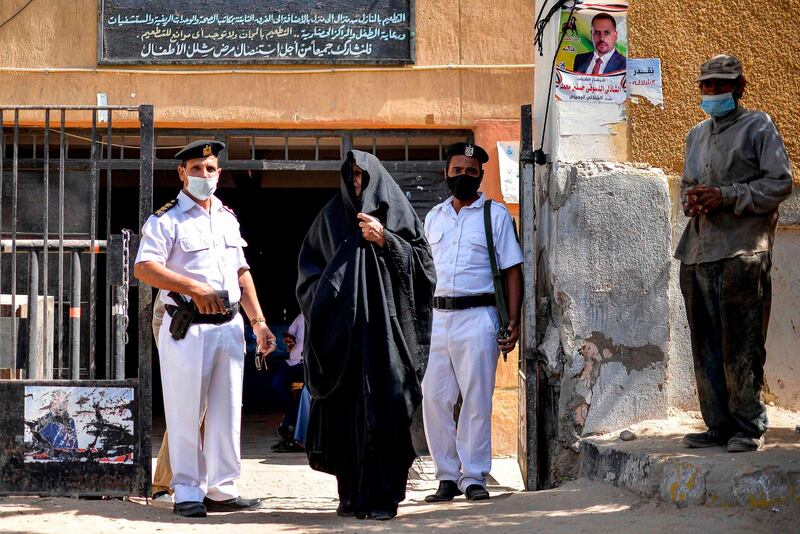 A woman walks out of a polling station past policemen in Esna, about 55 kilometres south of Egypt's southern city of Luxor, during the first stage of the lower house elections. AFP