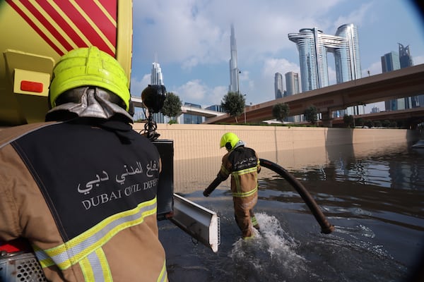 Dubai Civil Defence workers use a bowser to remove water from a flooded highway after the heaviest downpour since records began in 1949. Christopher Pike / Bloomberg