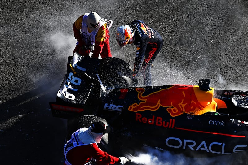 Red Bull's Max Verstappen and track marshals tend to the fire in his car after he retired from the race. Getty