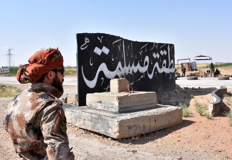 Syrian pro-government forces set up a road checkpoint next to a mural reading the Arabic: "Islamic State" after they took control of the northern Syrian town of Maskanah from the jihadists on June 5, 2017.  / AFP PHOTO / George OURFALIAN
