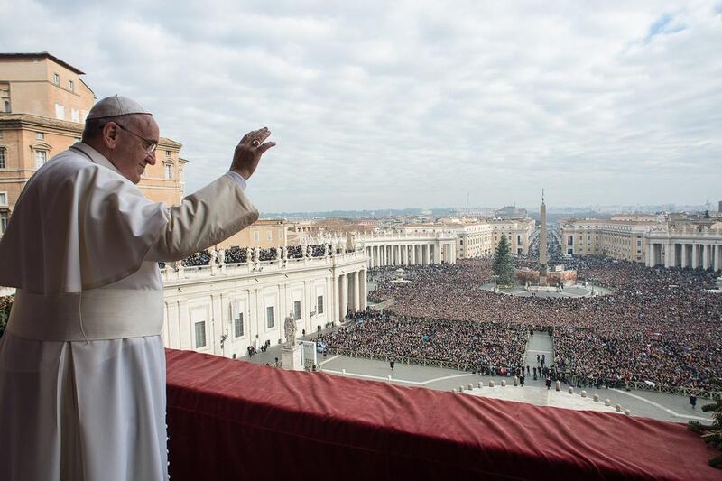 Pope Francis waves as he delivers his ‘Urbi et Orbi’ message from a balcony overlooking St Peter’s Square at the Vatican on December 25, 2014. Osservatore Romano / Reuters