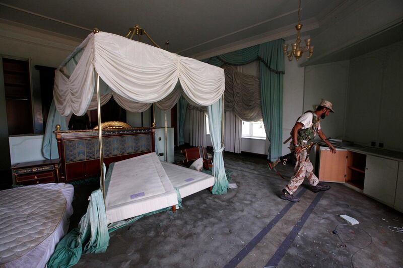 An anti-Gaddafi fighter searches inside the bedroom of one of Gaddafi's demolished houses in Sirte October 19, 2011. REUTERS/Saad Shalash  (LIBYA - Tags: POLITICS CIVIL UNREST) *** Local Caption ***  SS509_LIBYA_1019_11.JPG