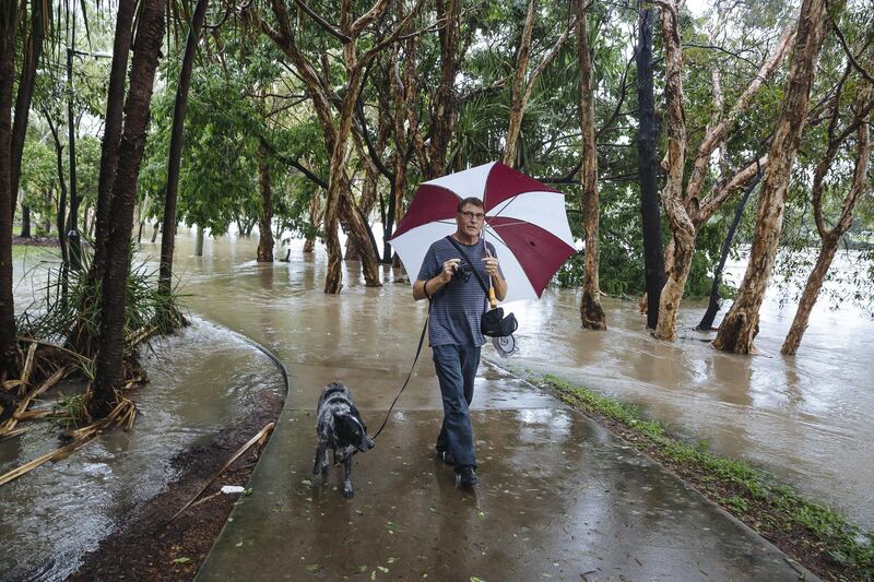 Wayne Clayton with Cooper walk through floodwaters in Mundingburra, a suburb of Townsville.  EPA