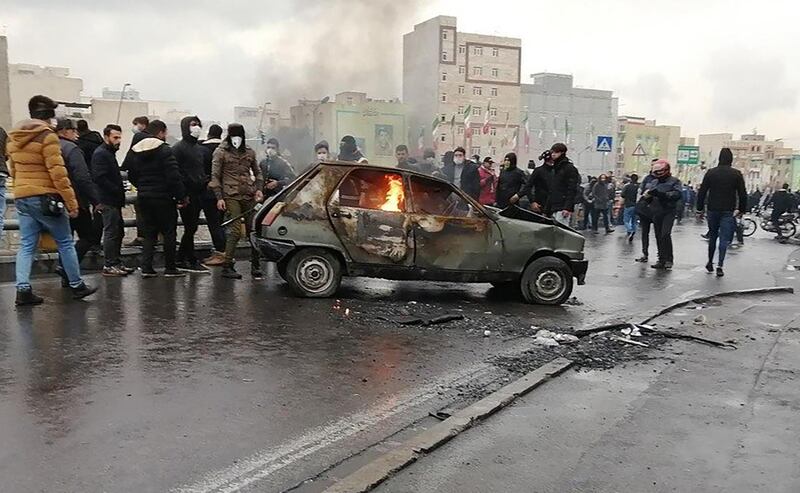 Iranian protesters gather around a burning car in the capital, Tehran on November 18.  AFP