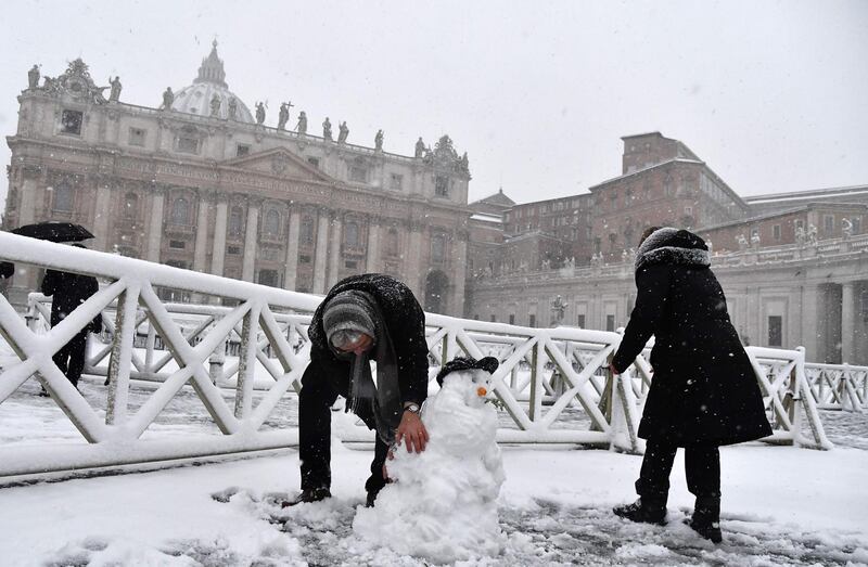 People build a snowman as it snows at St Peter's Square on February 26, 2018 at The Vatican. Tiziana Fabi / AFP