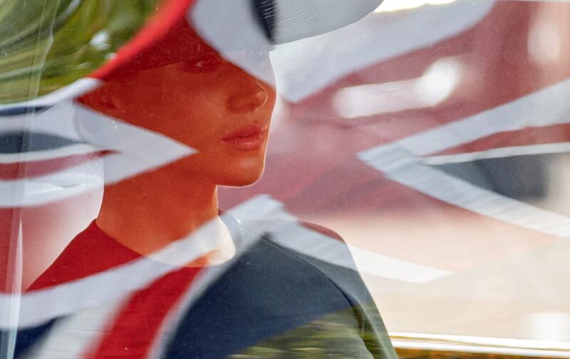 Meghan, Duchess of Sussex, sitting in a car as a British flag is reflected in its window. AFP