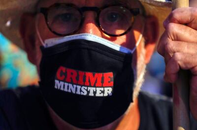 epa08563206 A man with a face mask reading 'Crime Minister' during a protest against Israeli Prime Minister Benjamin Netanyahu outside his residence in Jerusalem, Israel, 23 July 2020. Netanyahu faces an ongoing trial with indictments filed against him by the State Attorney's Office on a charges of fraud, bribery, and breach of trust.  EPA/ATEF SAFADI