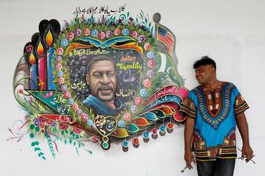 Pakistani truck-art painter Haider Ali, 40, poses for a photograph next to a mural, depicting George Floyd, who died in Minneapolis police custody in U.S., in Karachi, Pakistan, June 12, 2020. REUTERS/Akhtar Soomro