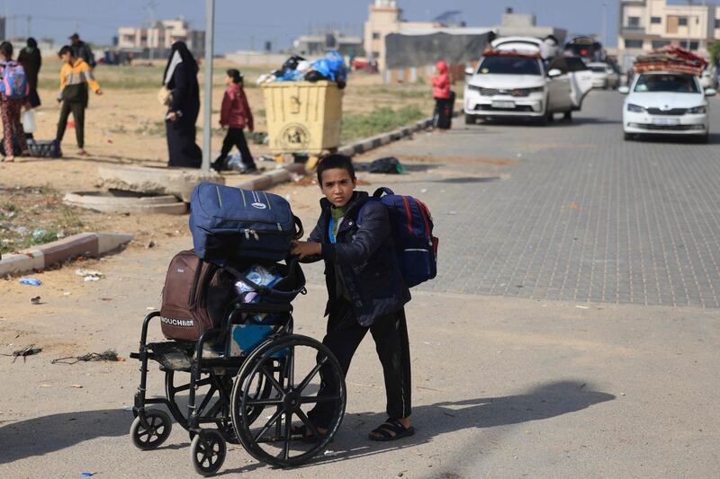 A Palestinian boy carries bags on a wheelchair as he flees with family members after receiving notice of an imminent Israeli strike. AFP