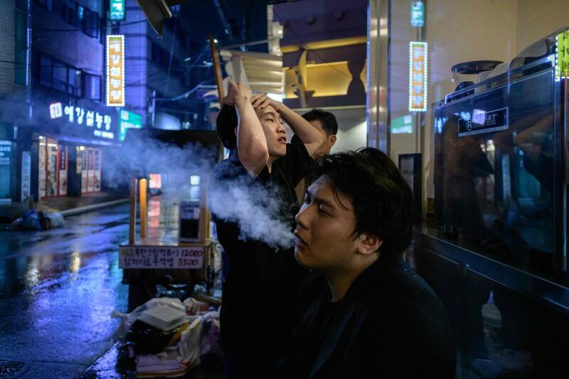 Singer Chu Yeonsik, centre, and guitarist Dominic Jin of post hardcore metal band Monsters Dive rest outside following their performance at a venue in Seoul. AFP