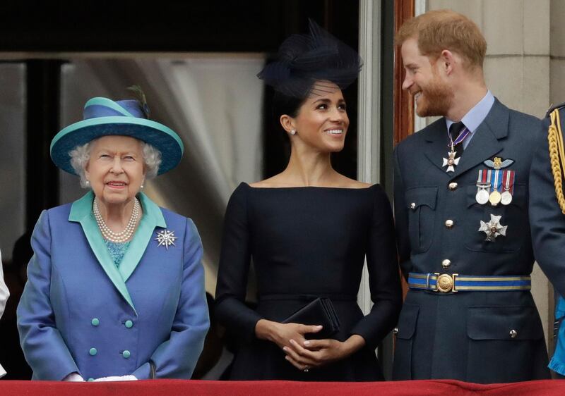 Britain's Queen Elizabeth II, Meghan the Duchess of Sussex and Prince Harry watch a flypast of Royal Air Force aircraft pass over Buckingham Palace in London. AP Photo