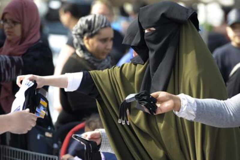 Samira, 36, wearing a niqab, the islamic full veil, buy socks at a market of Venissieux near Lyon, eastern France, on April 22, 2010. French government will pass a law to ban Muslim women from wearing a full-face veil in public, despite a warning from experts that such a law could be unconstitutional, it announced on April 21.      AFP PHOTO / PHILIPPE DESMAZES *** Local Caption ***  361307-01-08.jpg