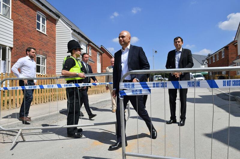 Britain's Home Secretary Sajid Javid, centre, exits the police cordon at Muggleton Road where counter-terrorism officers are investigating after a couple were left in a critical condition when they were exposed to the nerve agent Novichok, in Amesbury, England, Sunday July 8, 2018. Javid visited Amesbury and Salisbury in southwestern England to reassure residents that the risk to the public remains very low despite the recent poisoning of two people exposed to a deadly nerve agent. (Ben Birchall/PA via AP)