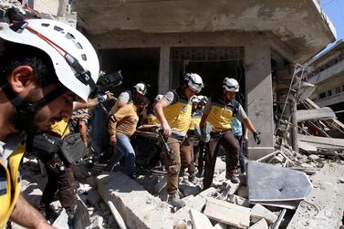 Members of the Syrian civil defence, known as the White Helmets, pull out bodies and wounded people from under the rubble following a Russian air strike on Maarat Al Numan in Syria's northwestern Idlib province on July 22, 2019. AFP