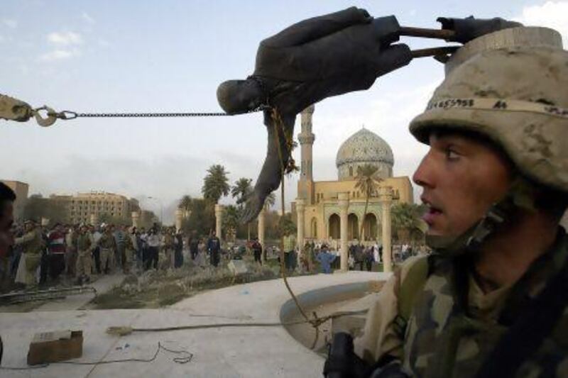 Iraqi civilians and US soldiers pull down a statue of Saddam Hussein in downtown Baghdad on April 9, 2003.