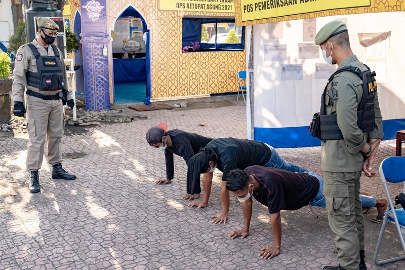 Men perform push-ups as a punishment for not wearing face masks, in Denpasar, Bali. EPA