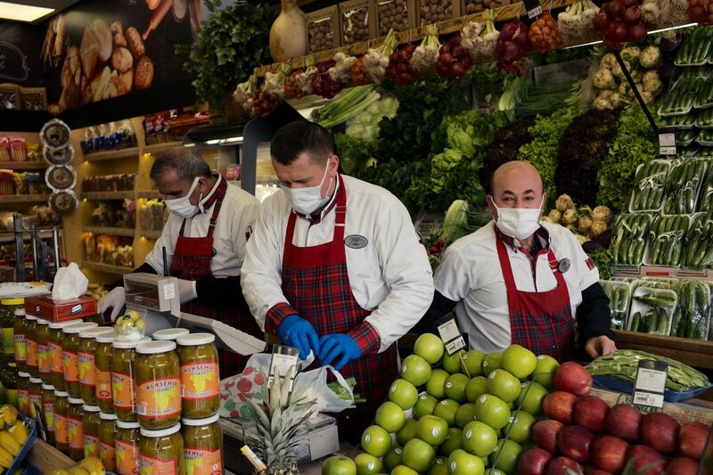 People wearing masks to help protect against the spread of coronavirus, work at a food market hours before a two-day weekend nationwide lockdown, in Ankara, Turkey, Friday, April 16, 2021. Turkey has registered more than 63,000 daily COVID-19 cases on Friday, as infections continue to soar to record levels. The Health Ministry also reported 289 COVID-19-linked deaths, the highest number of fatalities in a single day since the start of the outbreak.(AP Photo/Burhan Ozbilici)