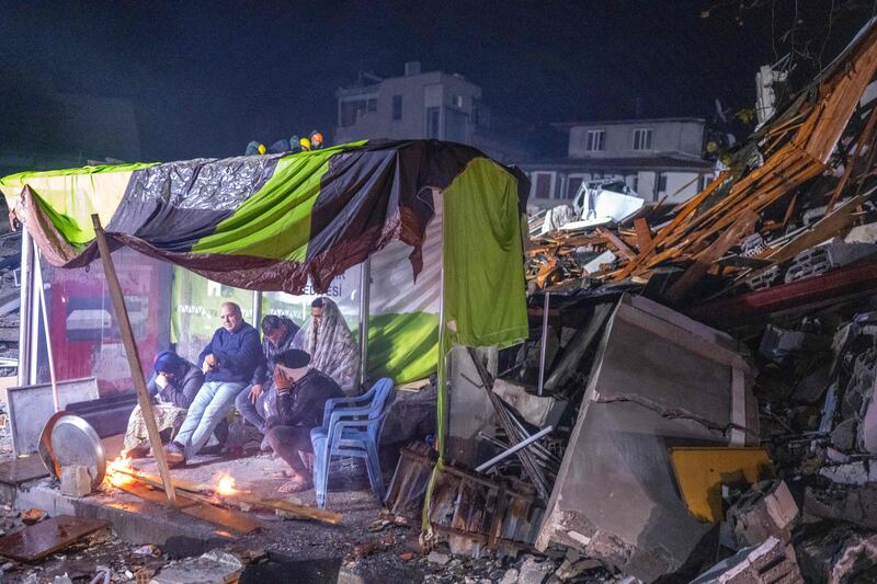 People rest next to fire amid the rubble in Hatay, after a 7. 8-magnitude earthquake struck Turkey's south-east. AFP