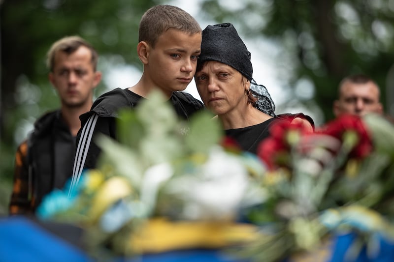Svitlana Nazarenko, sister of Mykhailo Tereshchenko, is comforted by her son during her brother's funeral in Kyiv. The Ukrainian soldier was killed in the Donbas region. Getty